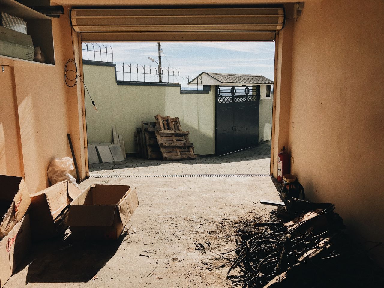 The Art of Drawing Readers In: Your attractive post title goes here View from inside a garage showing open roller shutter, cardboard boxes, and an outdoor concrete fence.