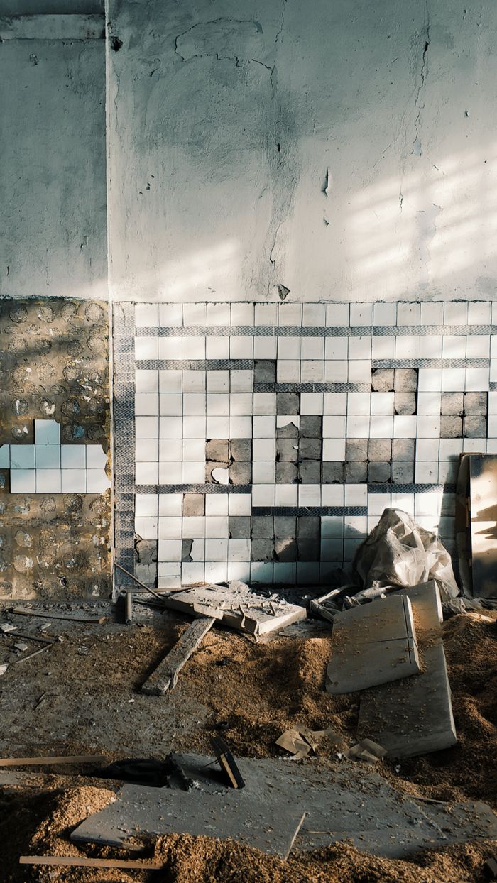 Home An abandoned, neglected room featuring damaged tiles and scattered debris; a testament to decay and decline.